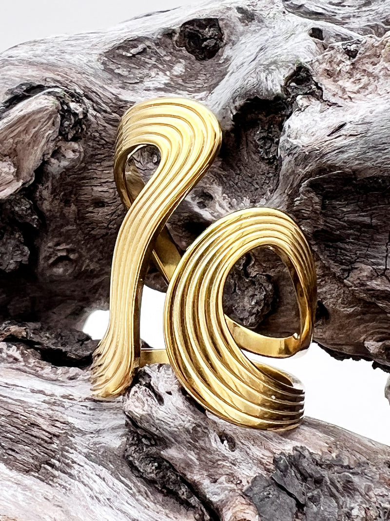 Gold spiral ring on a textured wooden surface