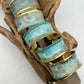 a collection of beautiful turquoise patina bracelets on a wooden display