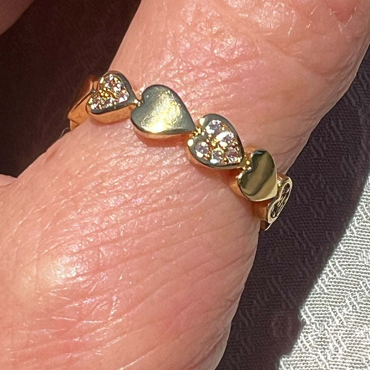 Gold-plated stainless steel heart ring on 
thumb. Adjustable, waterproof, and hypoallergenic