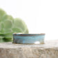 patina coated concave bracelet with turquoise hues on a rock
