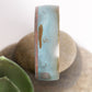 patina coated concave bracelet with turquoise hues on a rock
