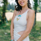 Woman smiling wearing a linen dress and golden spike earrings with brass diamond, triangle and long triangle spike in nature