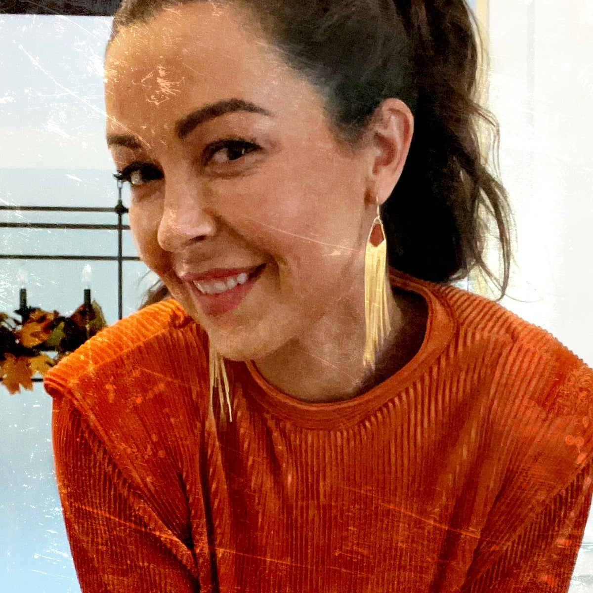 young lady with orange dress and fancy gold fringe earrings. 