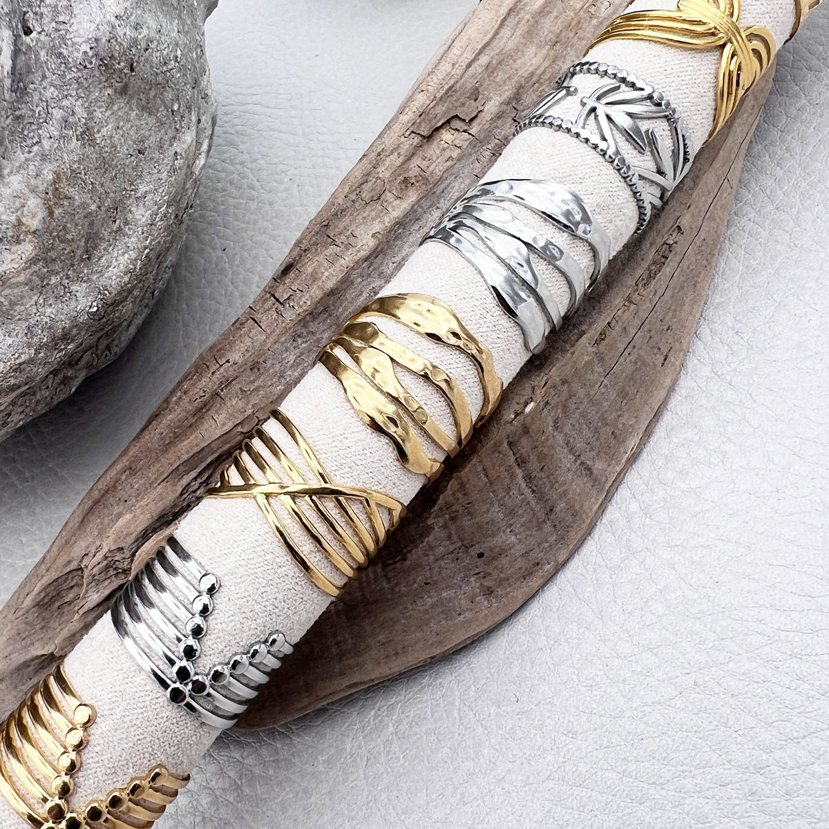 Adjustable stainless steel rings with gold and white design, displayed on a wooden branch.