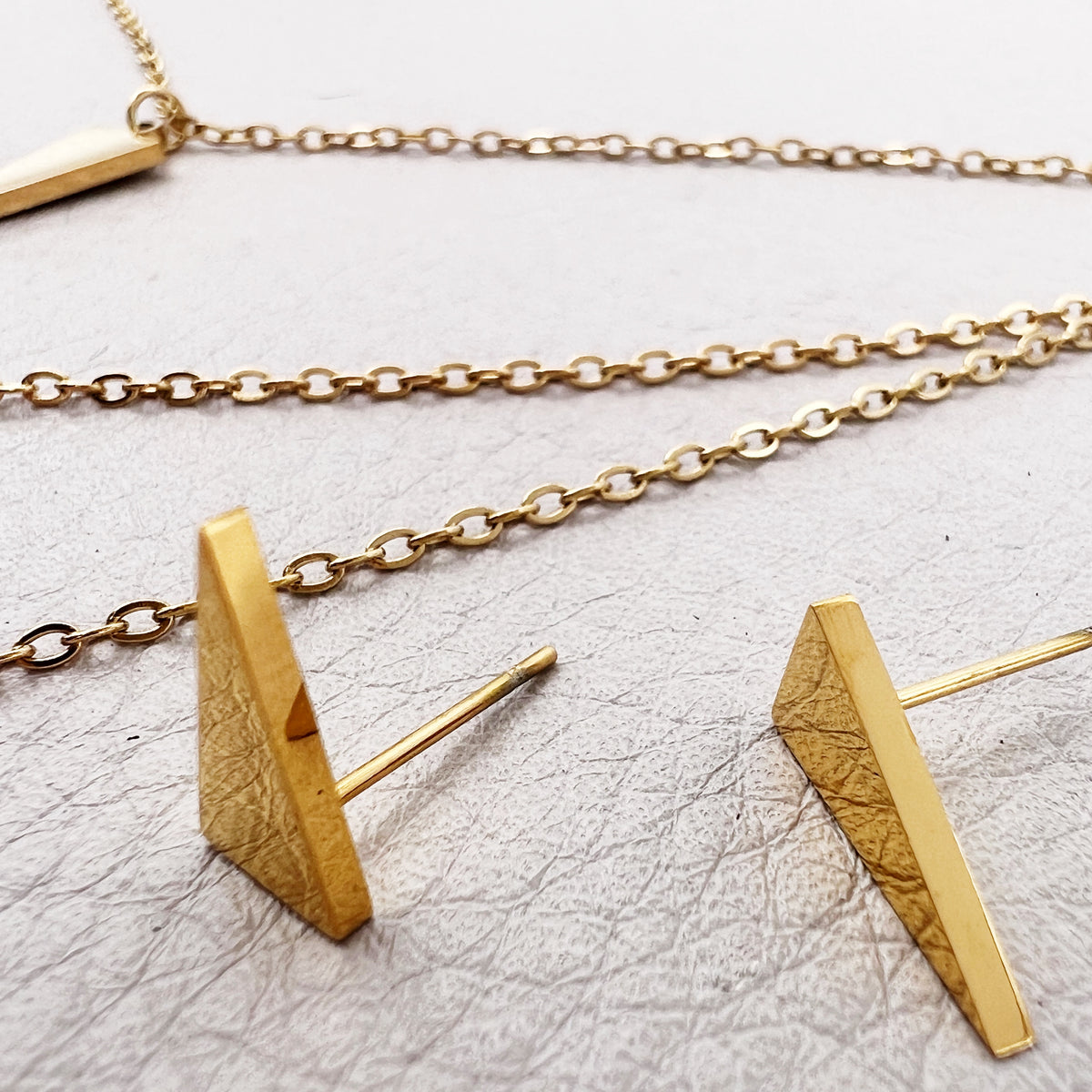 golden layered necklace with triangle, V shape and spike pendants
