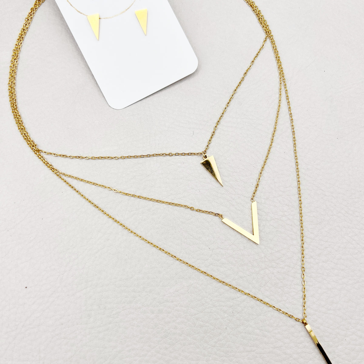 golden layered necklace with triangle, V shape and spike pendants