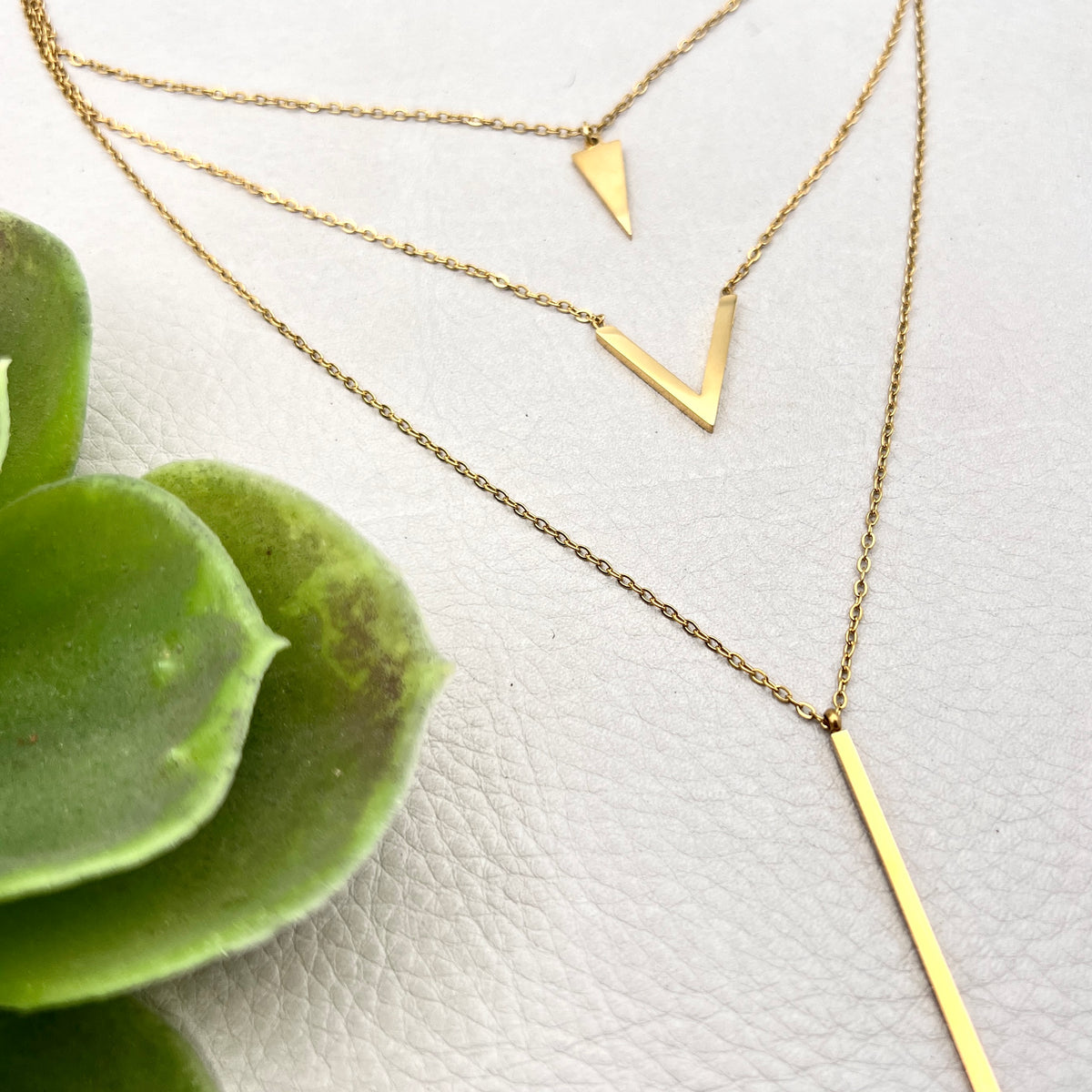 golden layered necklace with triangle, V shape and spike pendants