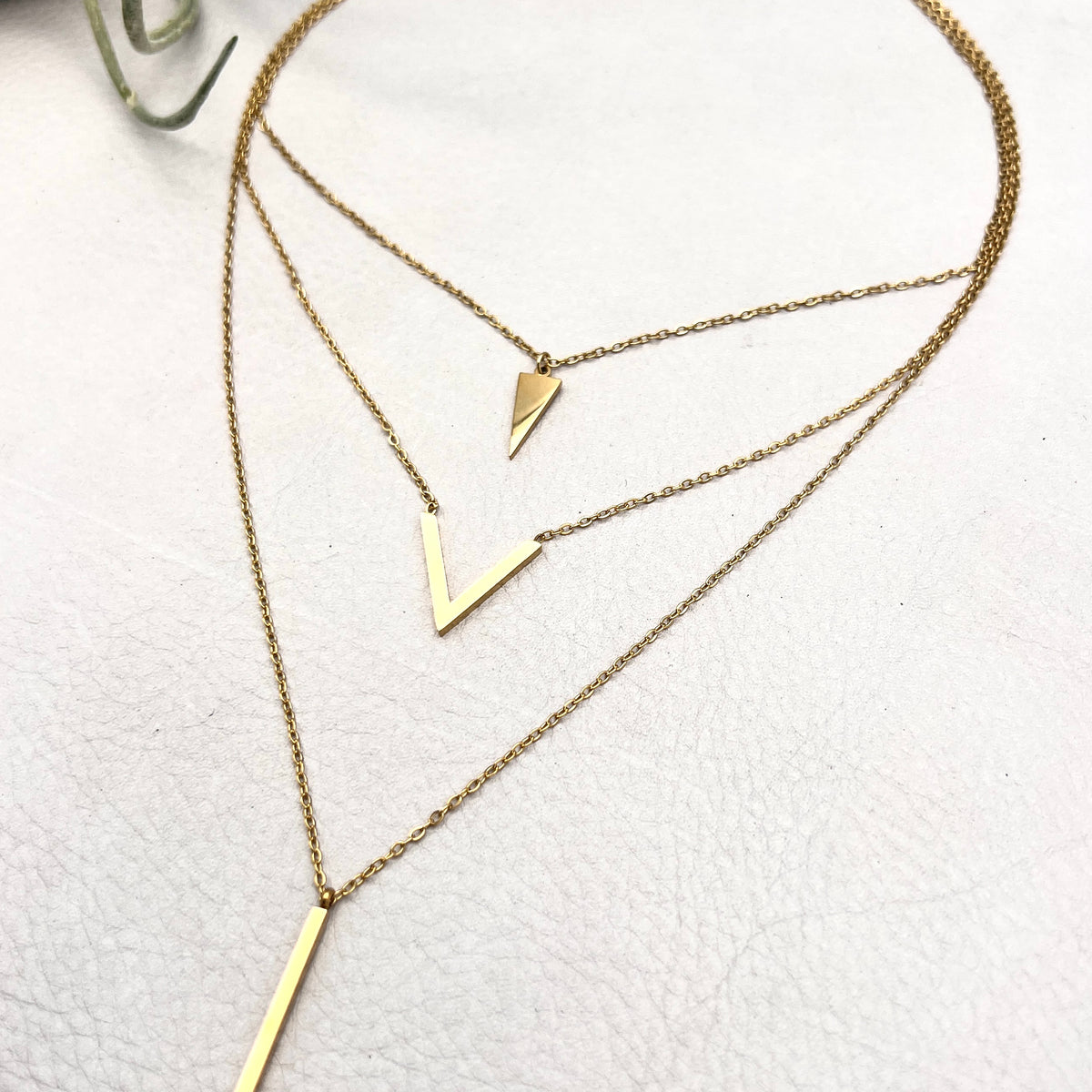 golden layered necklace with triangle, V shape and spike pendants