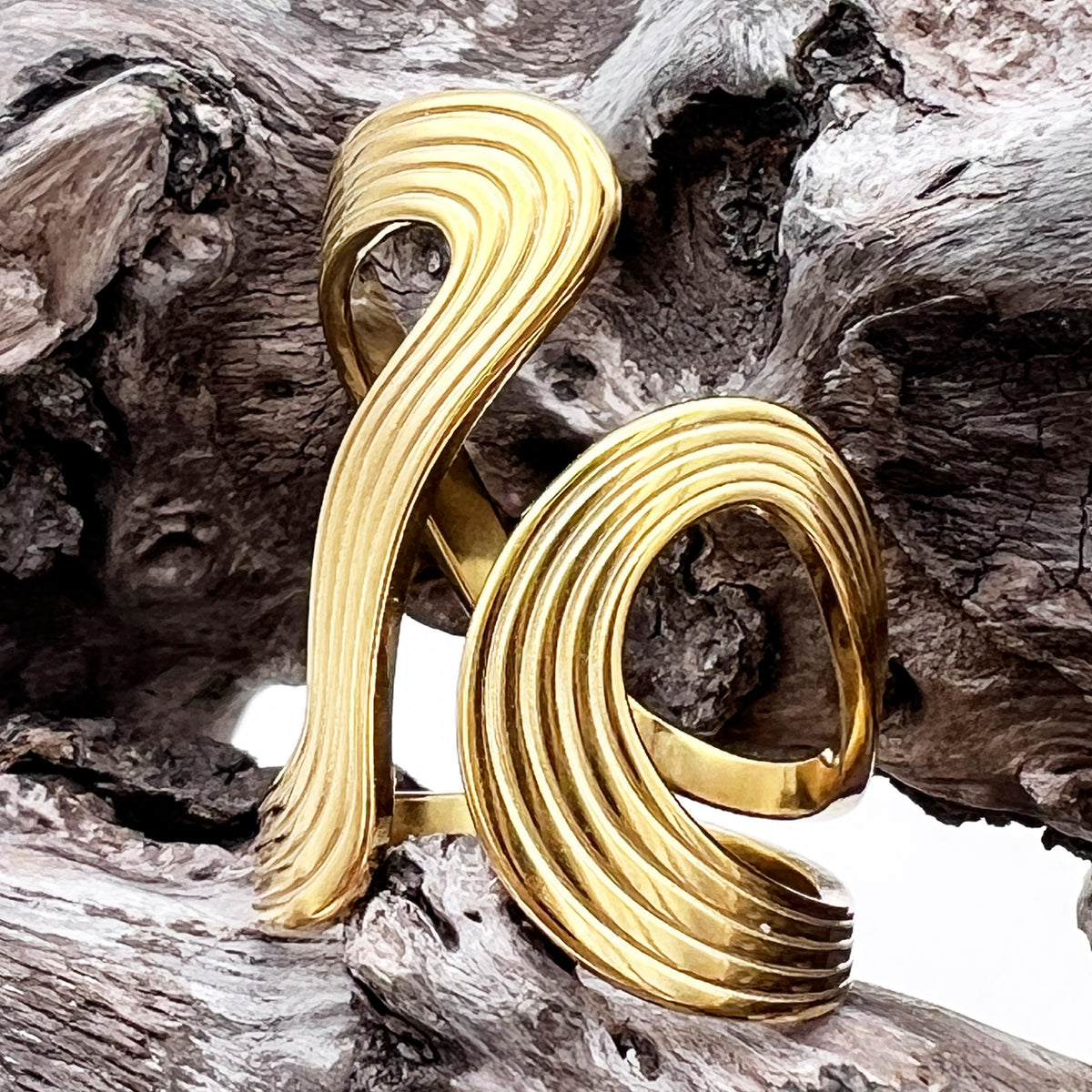Gold spiral ring on a textured wooden surface