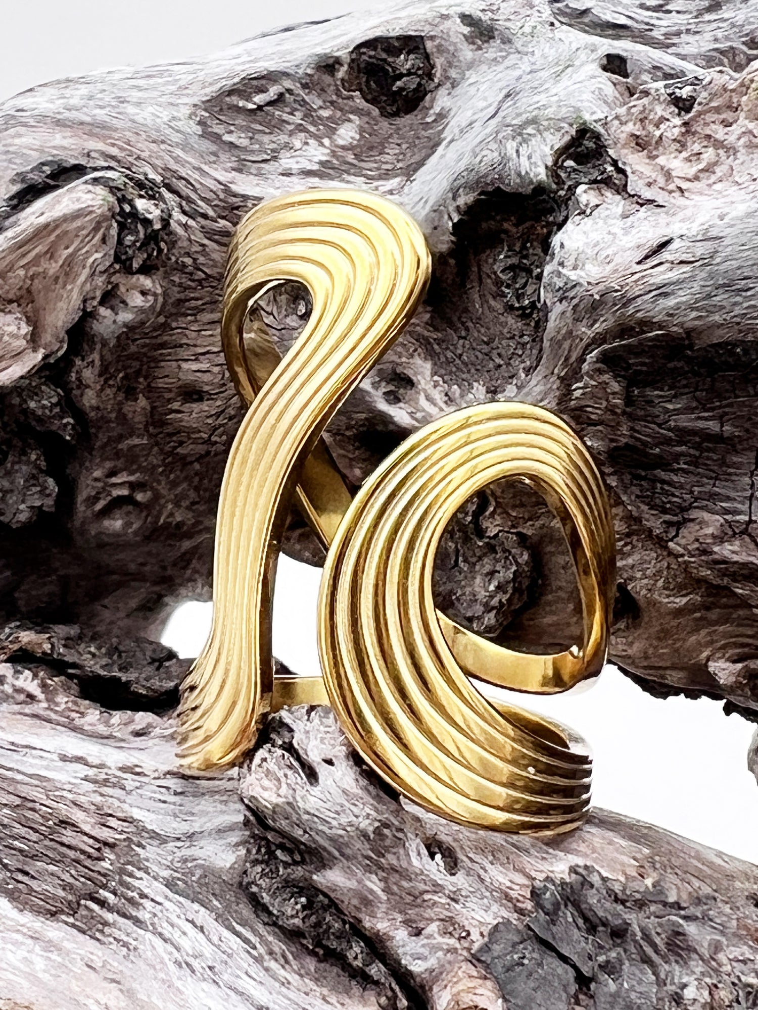 Gold spiral ring on a textured wooden surface