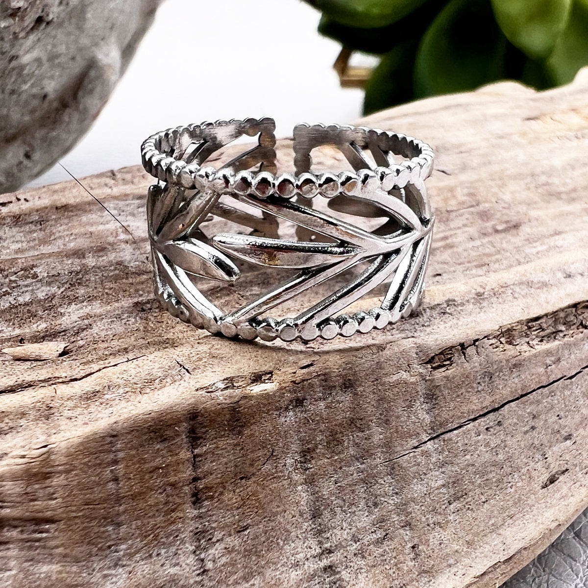 Adjustable stainless steel rings with gold and white design, displayed on a wooden branch.